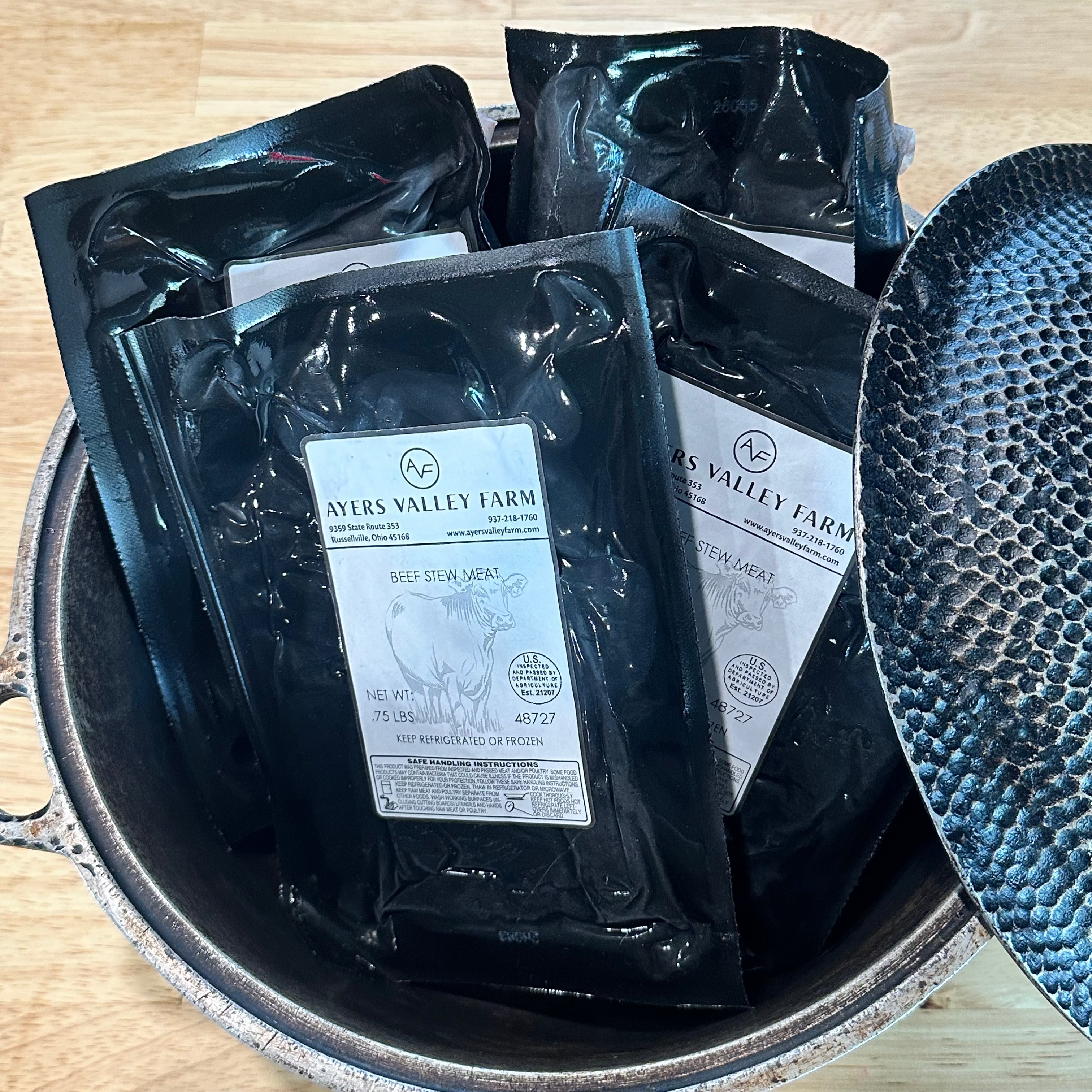 Grass fed and finished stew meat packages in a dutch oven